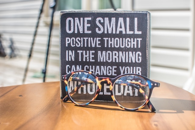 Pair of glasses in front of a motivational poster on a wooden table